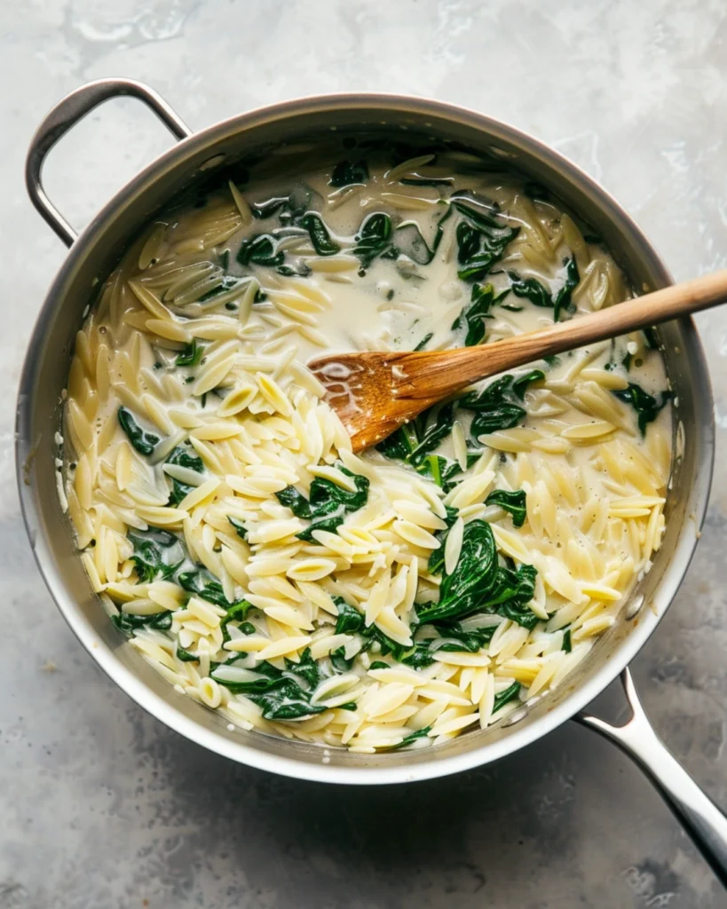 creamy spinach orzo with Parmesan – Irresistible Parmesan in 20 Mins 3 Orzo cooking with cream and spinach in skillet