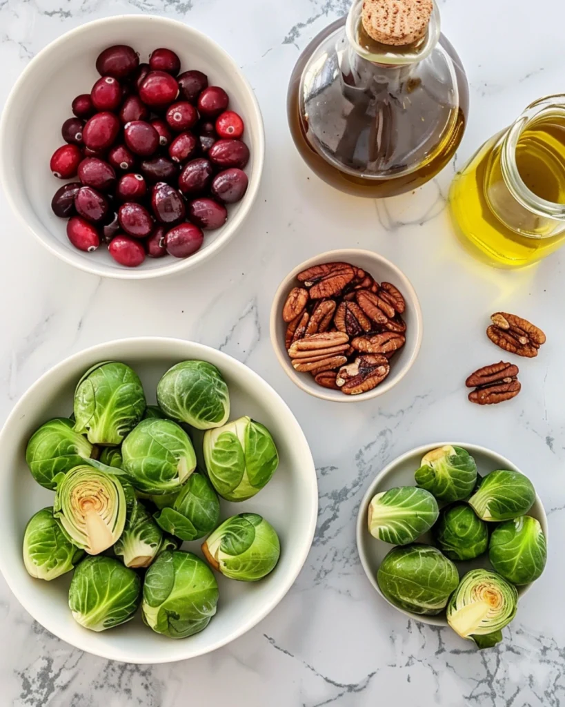 Maple Roasted Brussels Sprouts: 5 Irresistible Ways to Enjoy the Perfect Crispy Side 2 Brussels sprouts, olive oil, maple syrup, cranberries, and pecans arranged on marble counter.