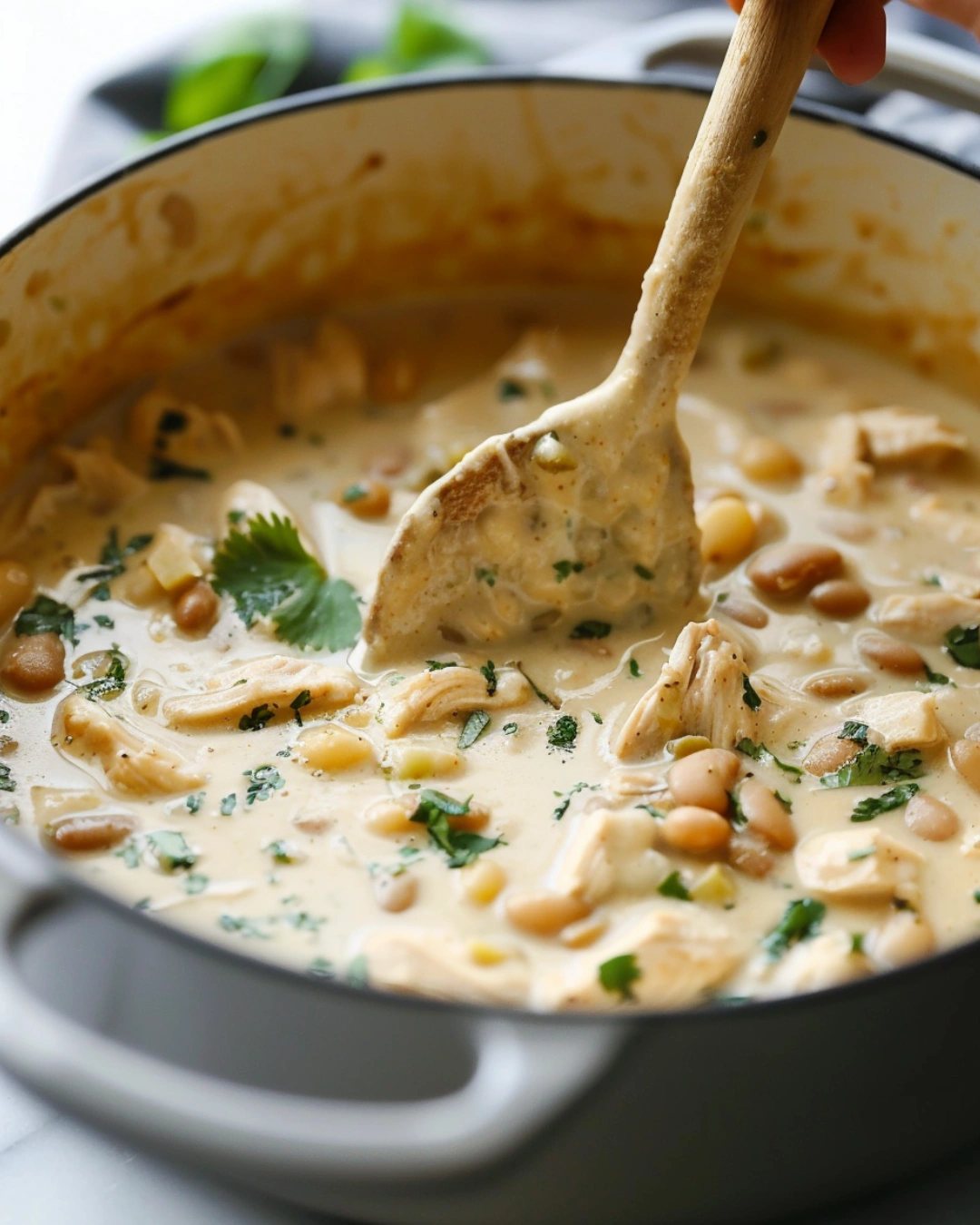 stirring sour cream into white chicken chili for creamy texture
