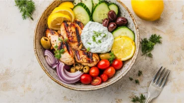 Greek chicken bowl with grilled chicken, vegetables, and feta in a rustic bowl