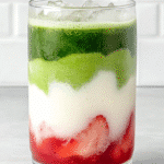 Strawberry matcha latte with layers of fresh strawberries, milk, and green tea in a clear glass