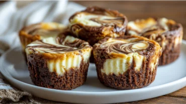 Brownie cheesecake cups with marbled cream cheese swirl on a white plate
