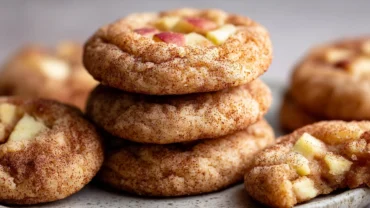 Soft chewy apple snickerdoodles stacked on a plate with cinnamon sugar coating