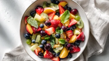 Modern fruit salad with peaches in white bowl