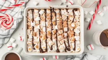 Close-up of Hot Cocoa Cheesecake Bars with marshmallows and chocolate drizzle.