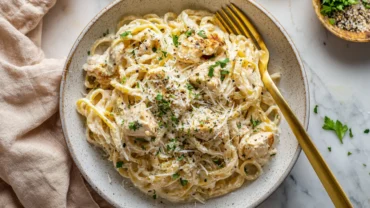 Top-down view of creamy garlic chicken pasta with parmesan and parsley.