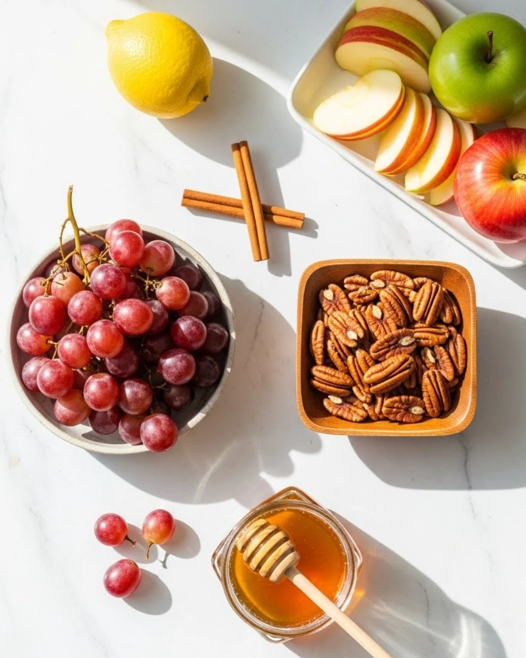 Fresh apples, red grapes, honey, lemon, and pecans for cinnamon apple salad