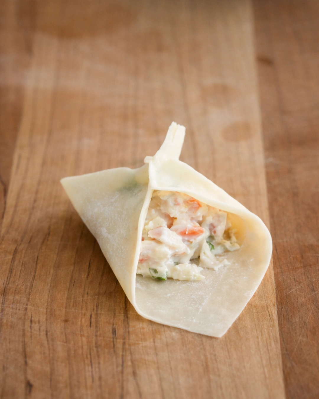 Filling a crab rangoon wrapper with creamy crab mixture before folding