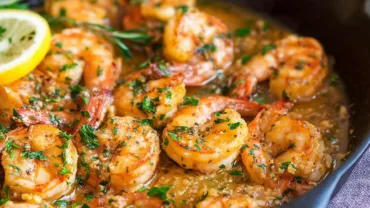 A cozy modern kitchen scene with a cast-iron skillet of Garlic Butter Shrimp — golden shrimp sizzling in melted butter, lemon slices, fresh parsley, soft daylight, rustic wood counter, linen napkin, shallow depth of field.