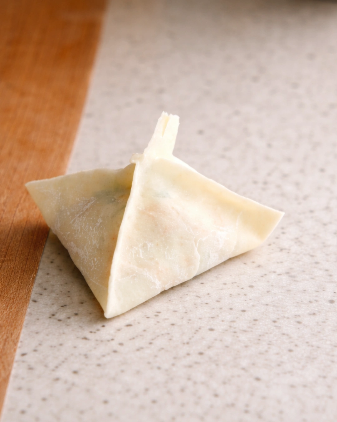 Folding a crab rangoon into a triangle shape before frying