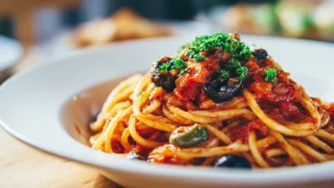 Pasta Puttanesca served with olives and parsley