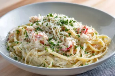 Copycat Red Lobster Crab Alfredo in a white bowl with Parmesan
