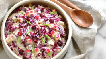 Cranberry apple coleslaw in ceramic bowl with autumn styling