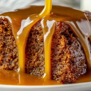 Decadent Sticky Toffee Pudding dripping with golden toffee sauce on white plate