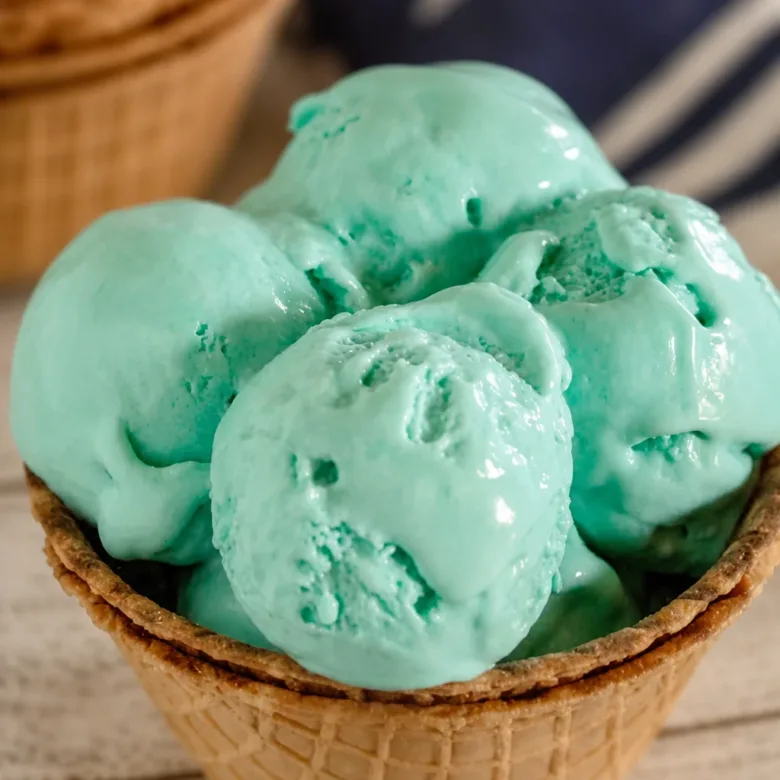A bowl of creamy blue raspberry ice cream garnished with fresh raspberries.