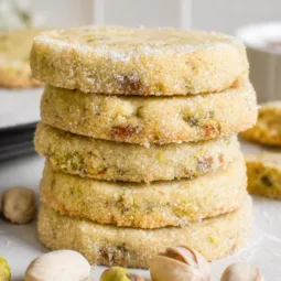 A plate of Pistachio Shortbread Cookies, golden and studded with pistachios.